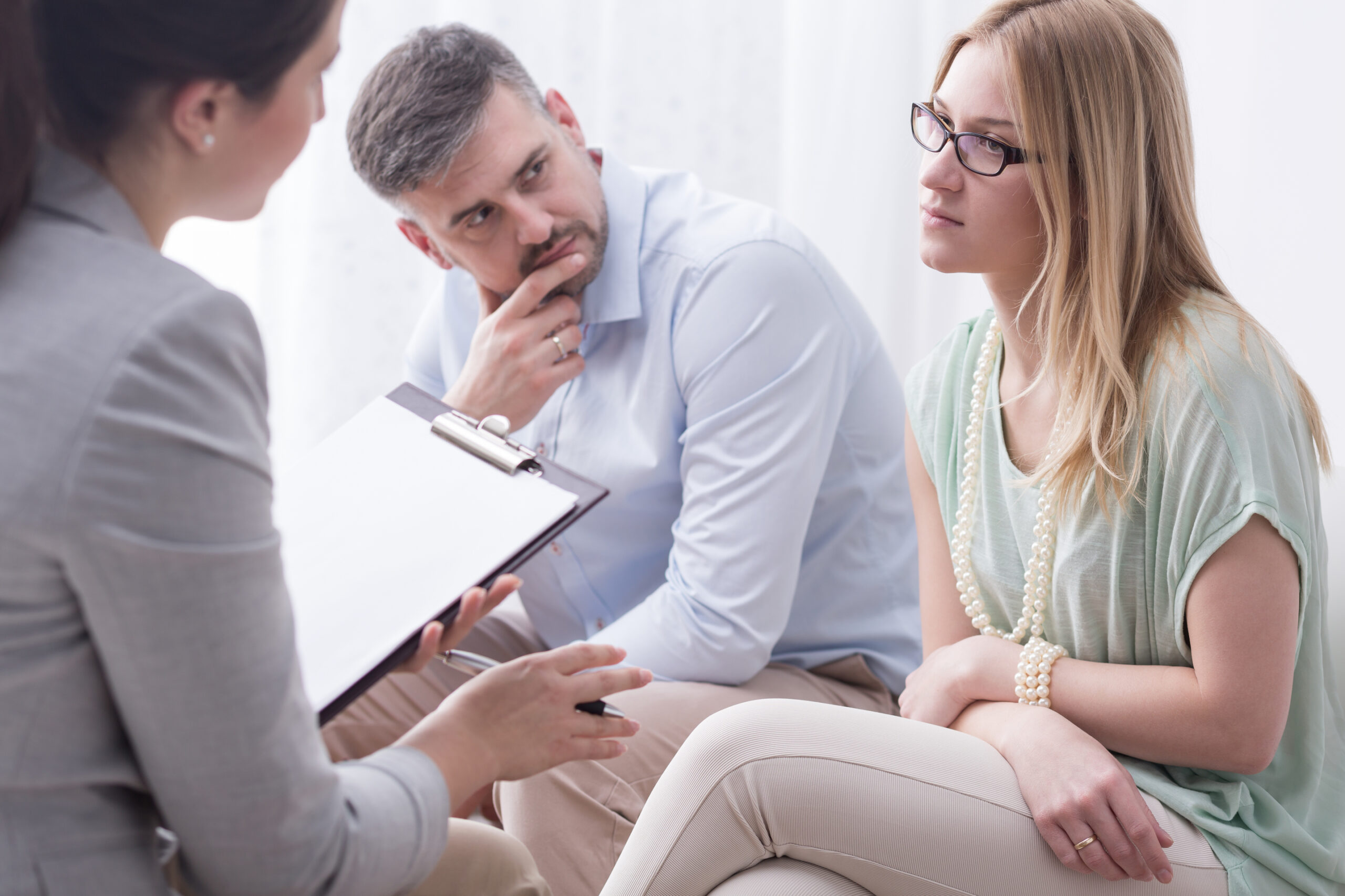 A therapist speaks with a couple in a counseling session, focusing on their concerns. The atmosphere suggests a supportive environment for discussion.