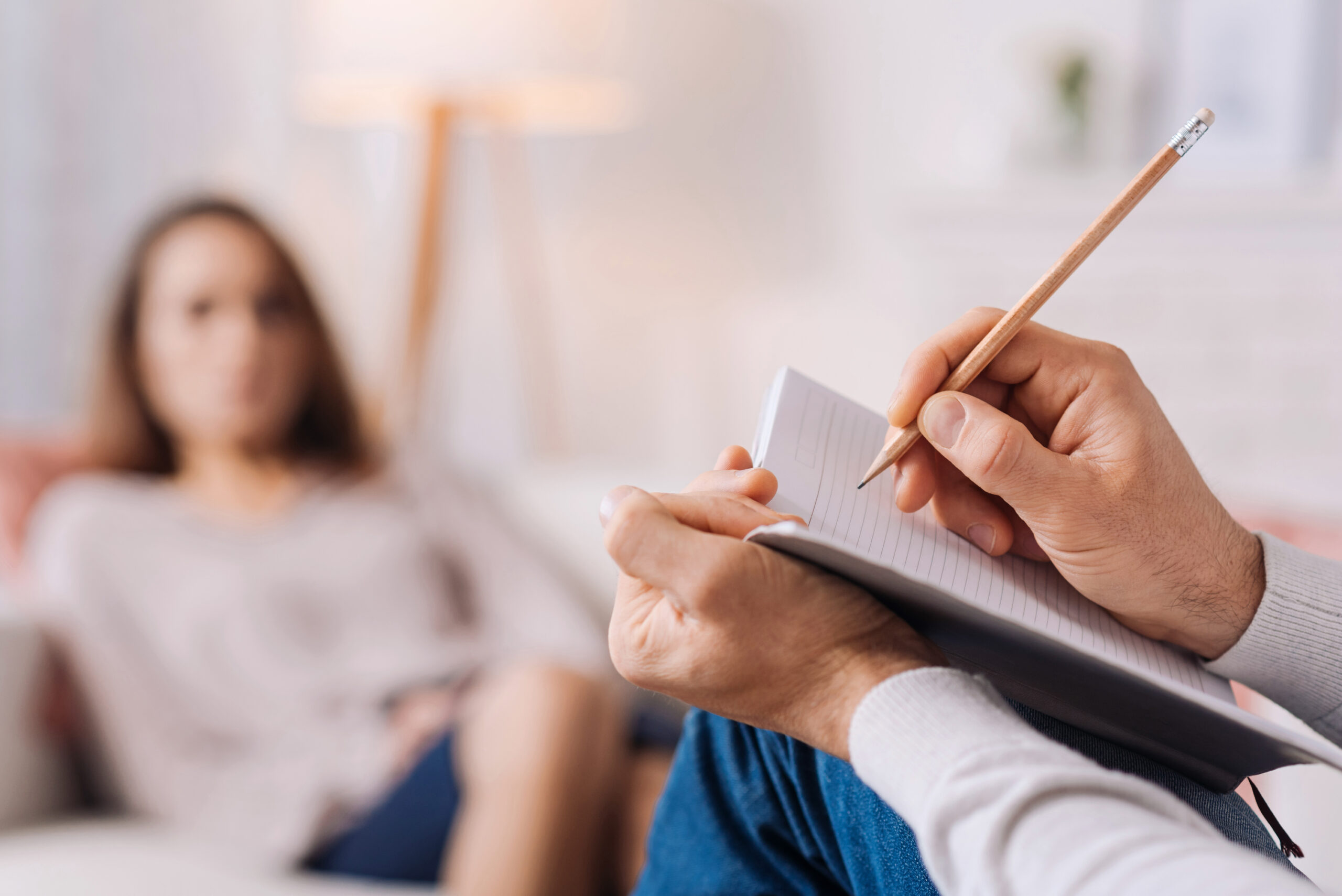 A therapist takes notes while a patient shares thoughts during a session, highlighting the therapeutic conversation in a cozy setting.